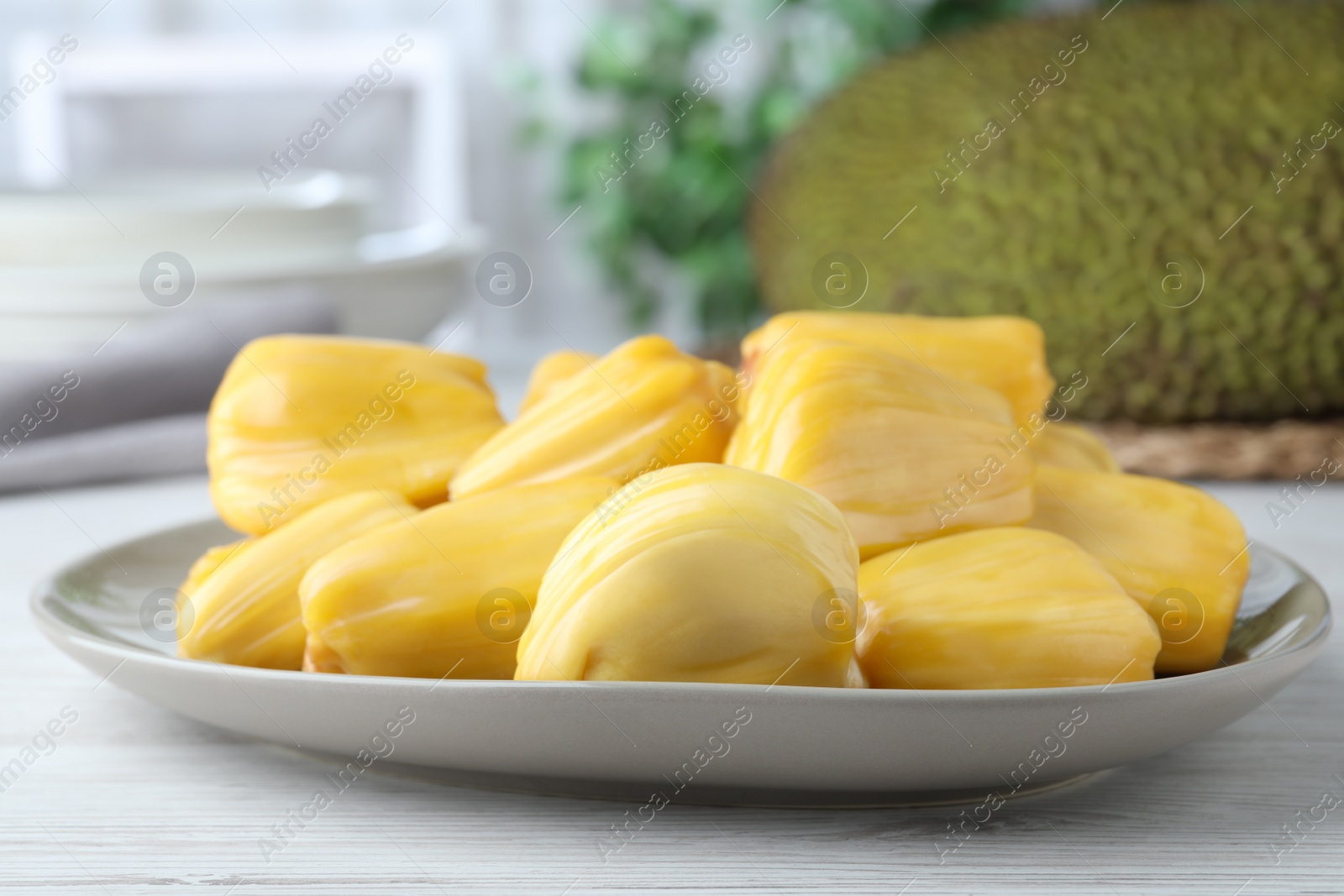 Photo of Fresh exotic jackfruit bulbs on white wooden table, closeup