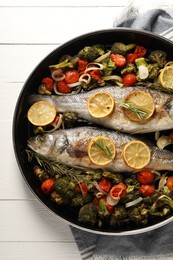 Baked fish with vegetables, rosemary and lemon on white wooden table, top view