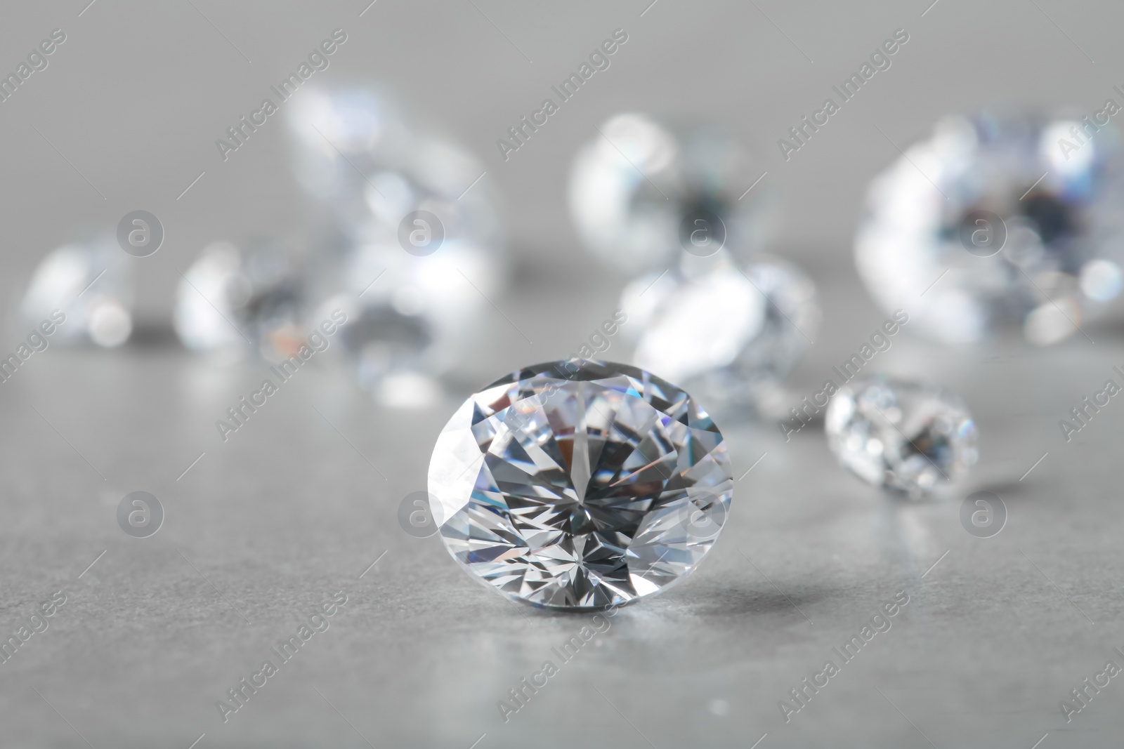 Photo of Beautiful shiny diamond on gray table, space for text