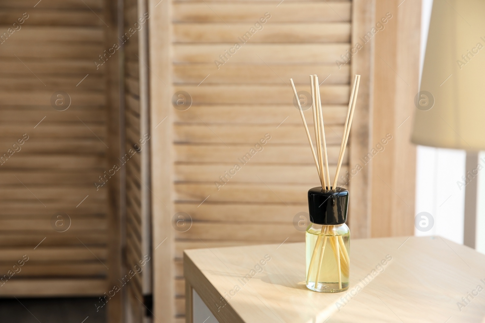 Photo of Aromatic reed air freshener on table indoors