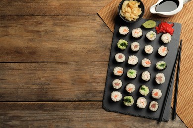Photo of Tasty sushi rolls served on wooden table, flat lay. Space for text
