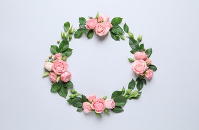 Photo of Wreath made of beautiful flowers and green leaves on light background, flat lay. Space for text