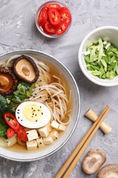 Photo of Delicious vegetarian ramen served on grey table, flat lay. Noodle soup