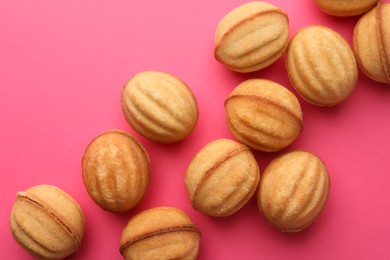 Photo of Homemade walnut shaped cookies with condensed milk on pink background, flat lay