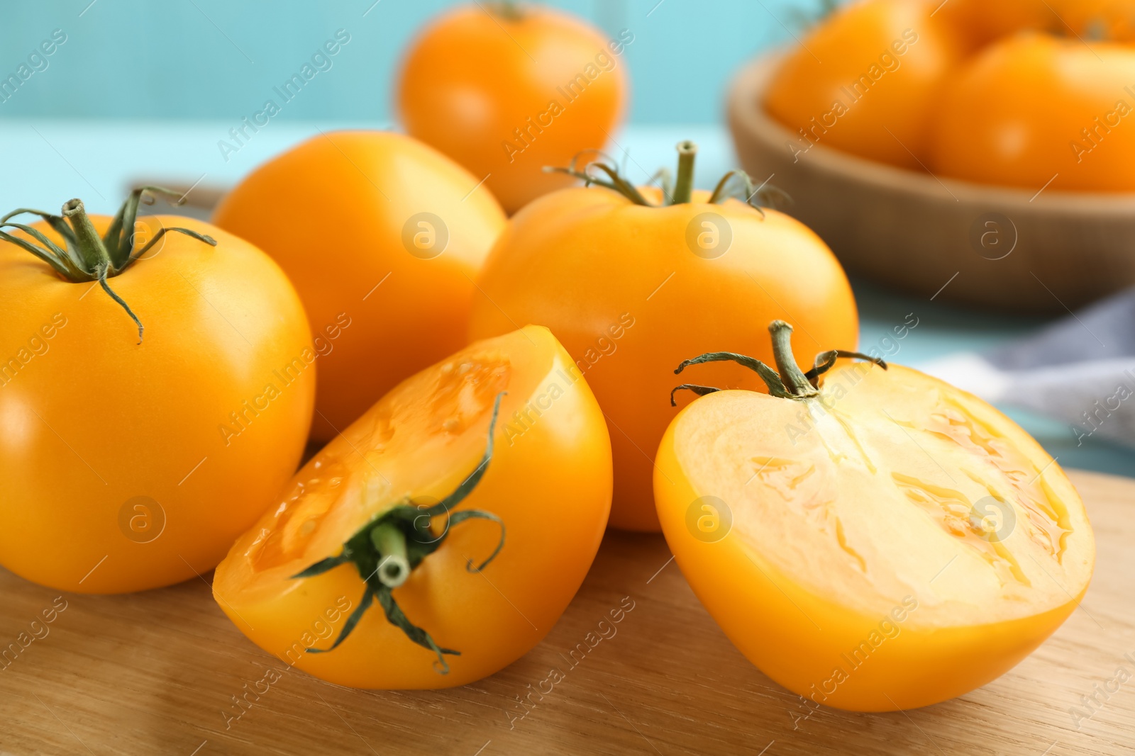 Photo of Ripe yellow tomatoes on wooden board, closeup