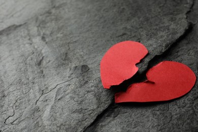 Photo of Halves of torn red paper heart on dark grey table, space for text. Broken heart