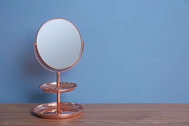 Mirror with accessory holder on table near color wall