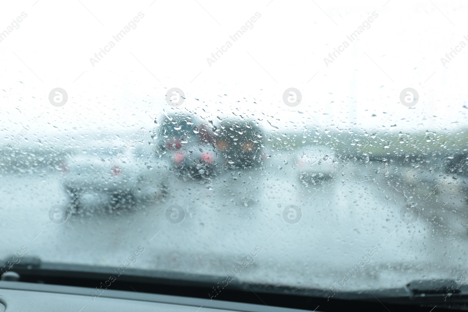 Photo of Blurred view of suburban road through wet car window. Rainy weather