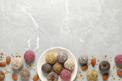 Photo of Delicious vegan candy balls and nuts on light grey marble table, flat lay. Space for text