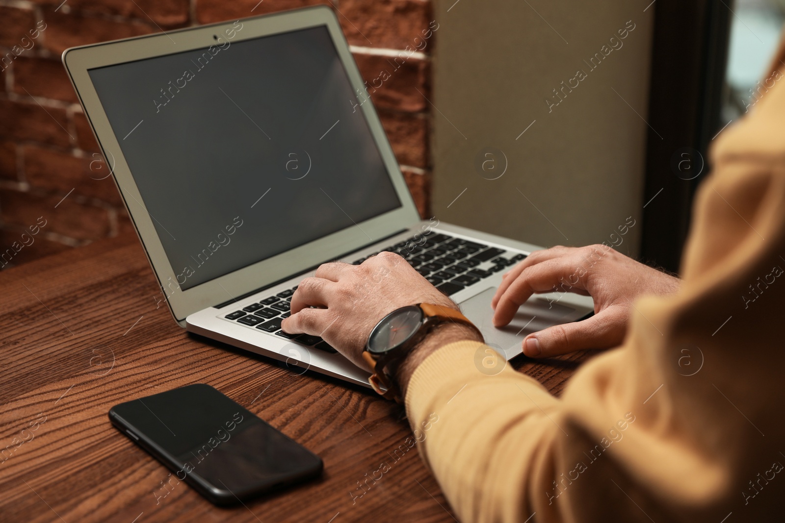 Photo of Male blogger working with laptop at table in cafe, closeup