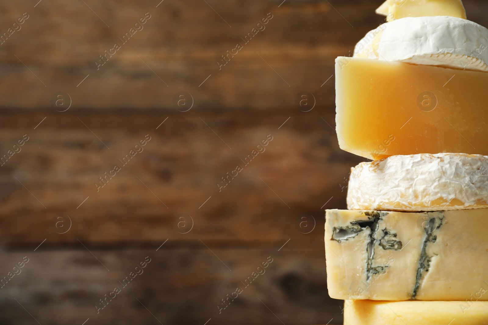 Photo of Different types of delicious cheese against wooden background, closeup. Space for text