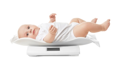 Photo of Cute little baby lying on scales against white background