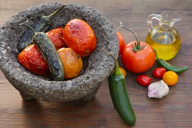 Ingredients for tasty salsa sauce and stone bowl on wooden table