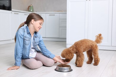 Little child feeding cute puppy in kitchen. Lovely pet