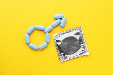 Photo of Male sign made of pills and condom on orange background, flat lay. Potency problem