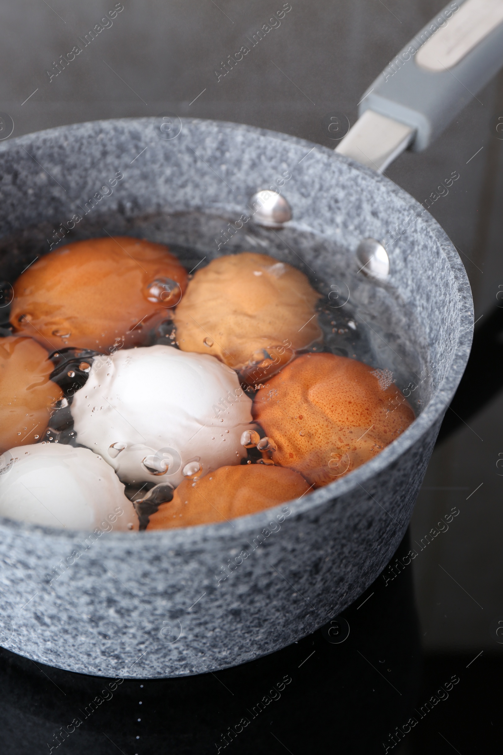 Photo of Chicken eggs boiling in saucepan on electric stove, closeup