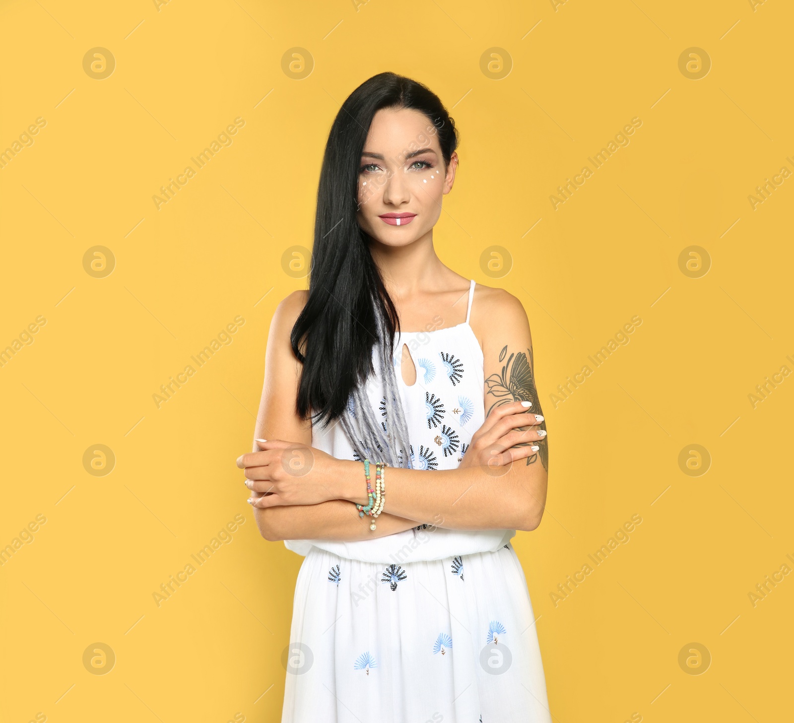 Photo of Portrait of young hippie woman with boho makeup in stylish outfit on color background