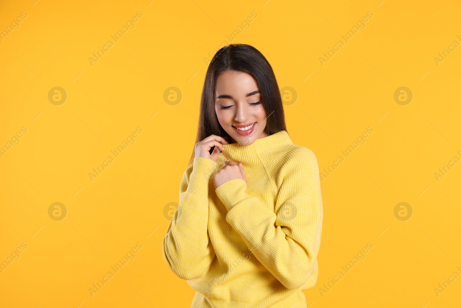 Photo of Beautiful young woman wearing warm sweater on yellow background