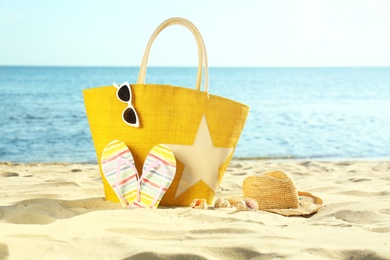 Composition with stylish beach accessories on sand near sea