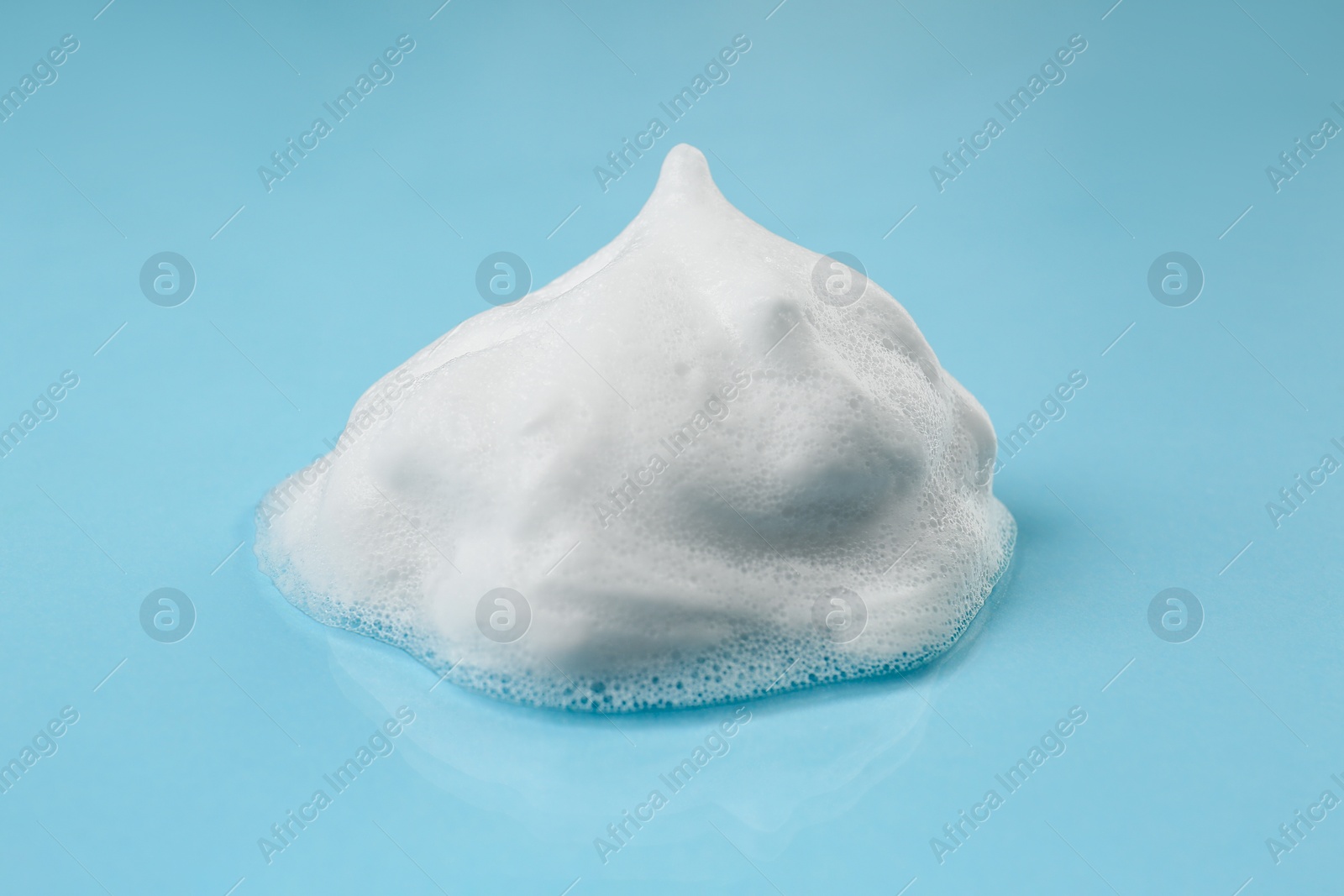 Photo of Foam on light blue background. Face cleanser, skin care cosmetic