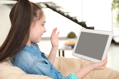 Cute girl using video chat on tablet at home, space for text