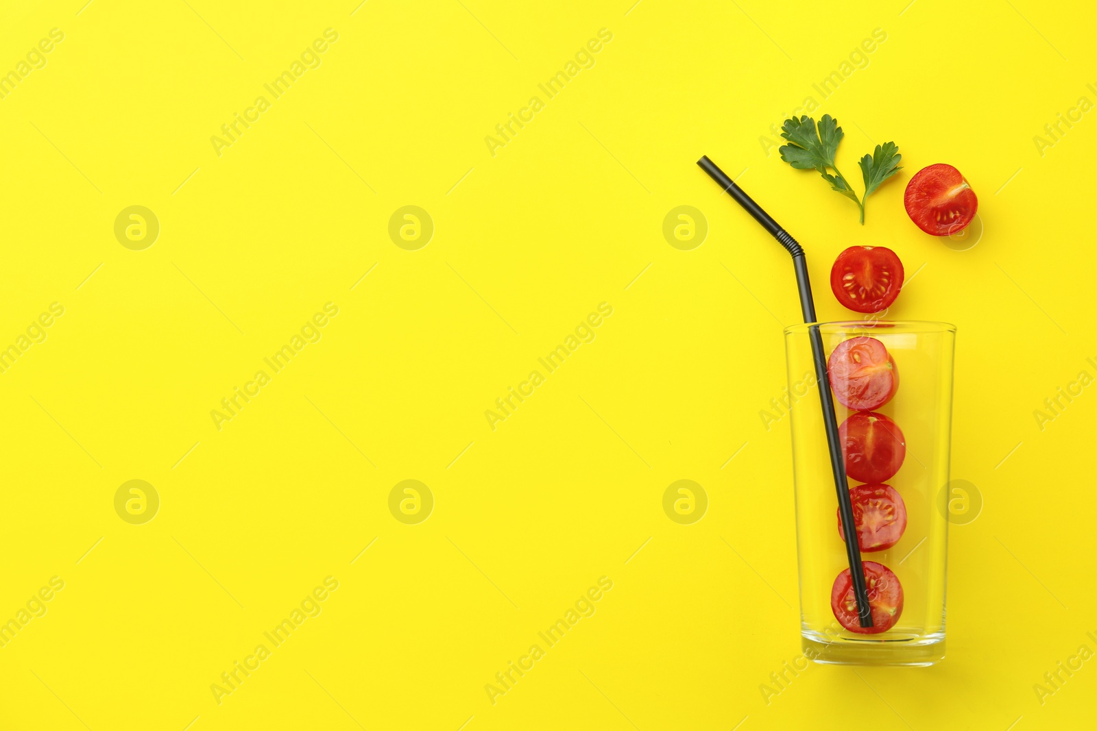 Photo of Glass, fresh tomatoes, parsley and straw on yellow background, flat lay. Space for text