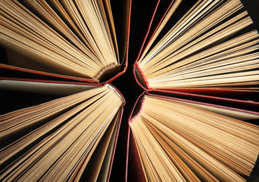 Photo of Many different hardcover books on dark background, top view