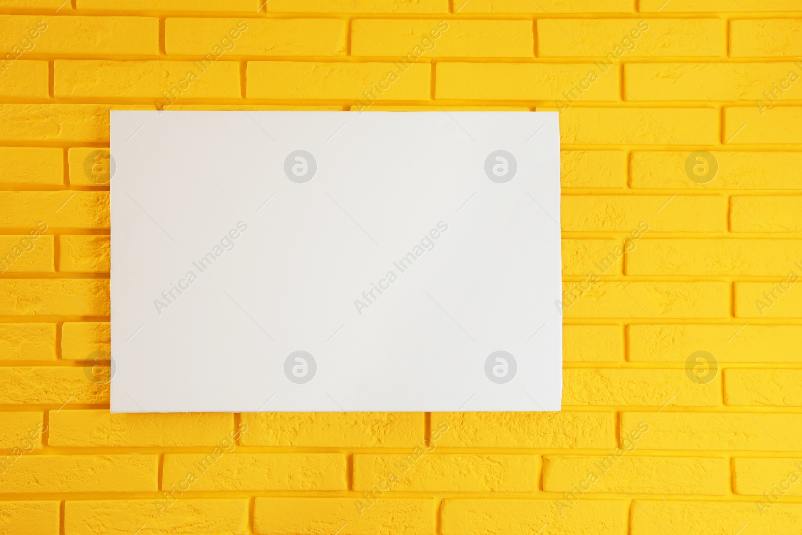 Photo of Blank canvas on yellow brick wall. Space for design