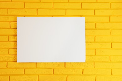 Photo of Blank canvas on yellow brick wall. Space for design