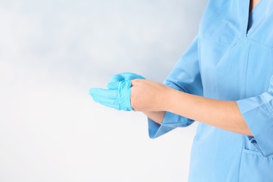 Doctor taking off medical gloves on color background. Space for text