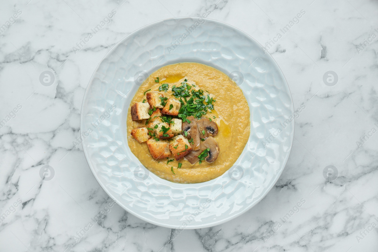 Photo of Delicious cream soup with mushrooms and croutons on white marble table, top view