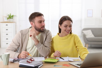 Photo of Young couple discussing family budget at table in living room