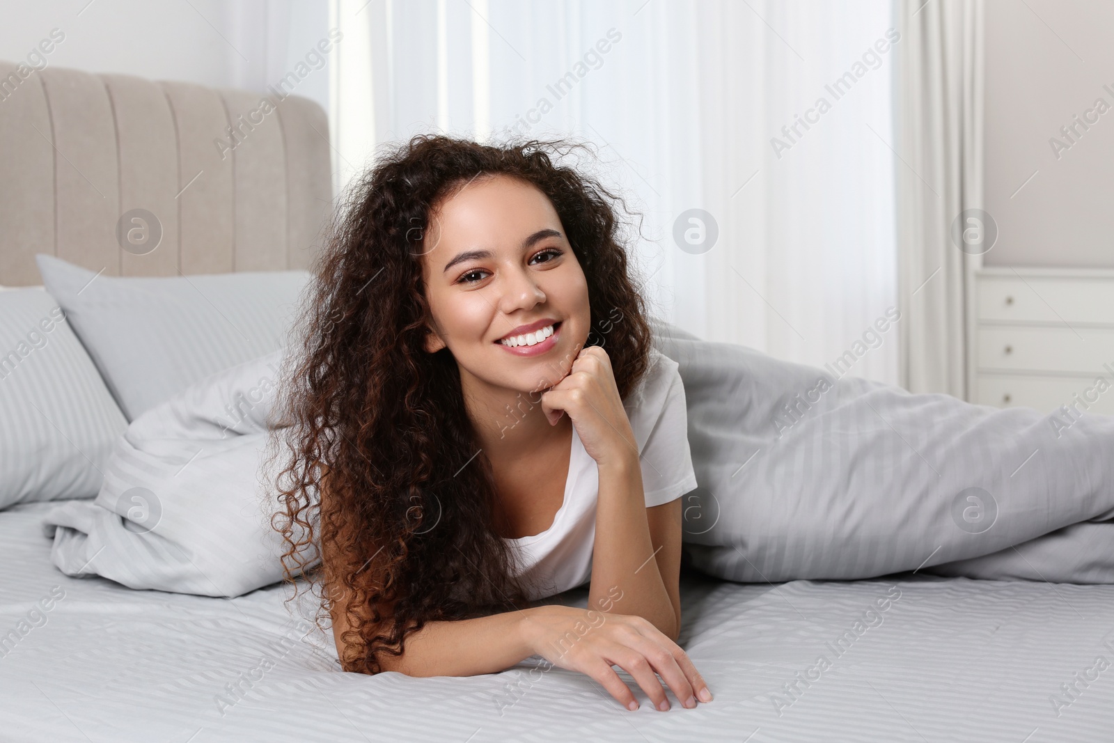 Photo of Happy beautiful African American woman lying in bed at home