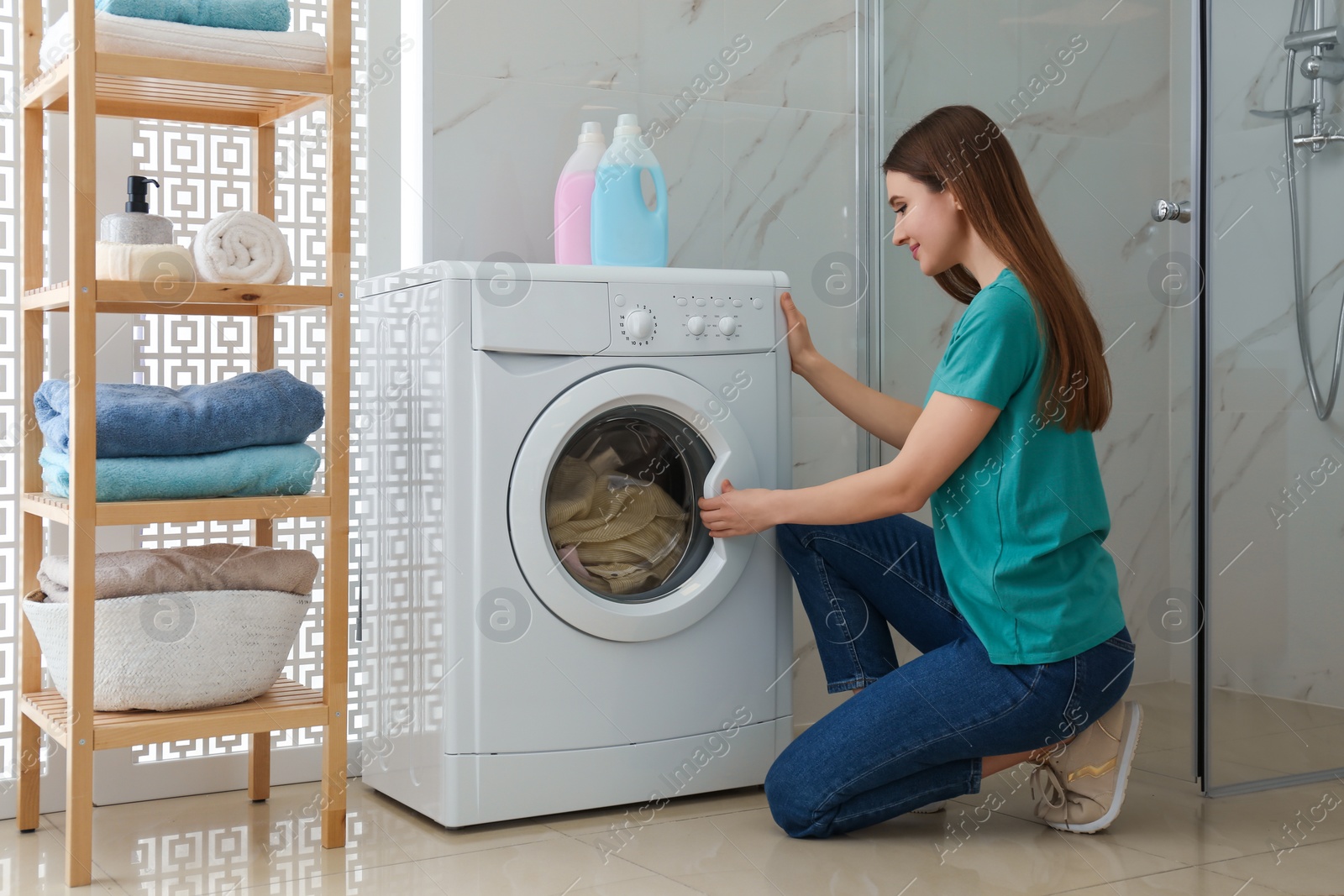 Photo of Woman near washing machine in bathroom. Laundry day