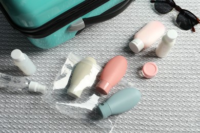 Photo of Cosmetic travel kit and plastic bag near suitcase on bed