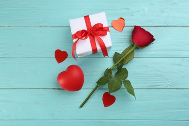 Photo of Gift box, rose and red hearts on turquoise wooden background, flat lay. Valentine's Day celebration