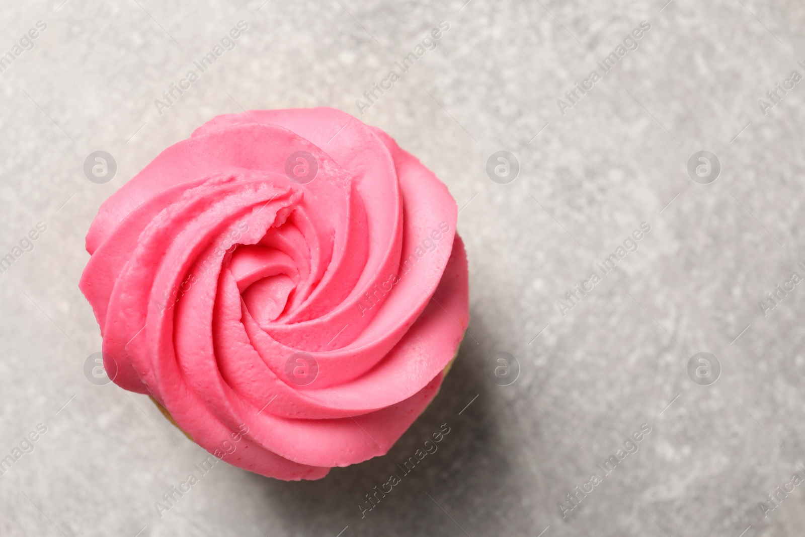 Photo of Delicious cupcake with bright cream on gray table, top view. Space for text