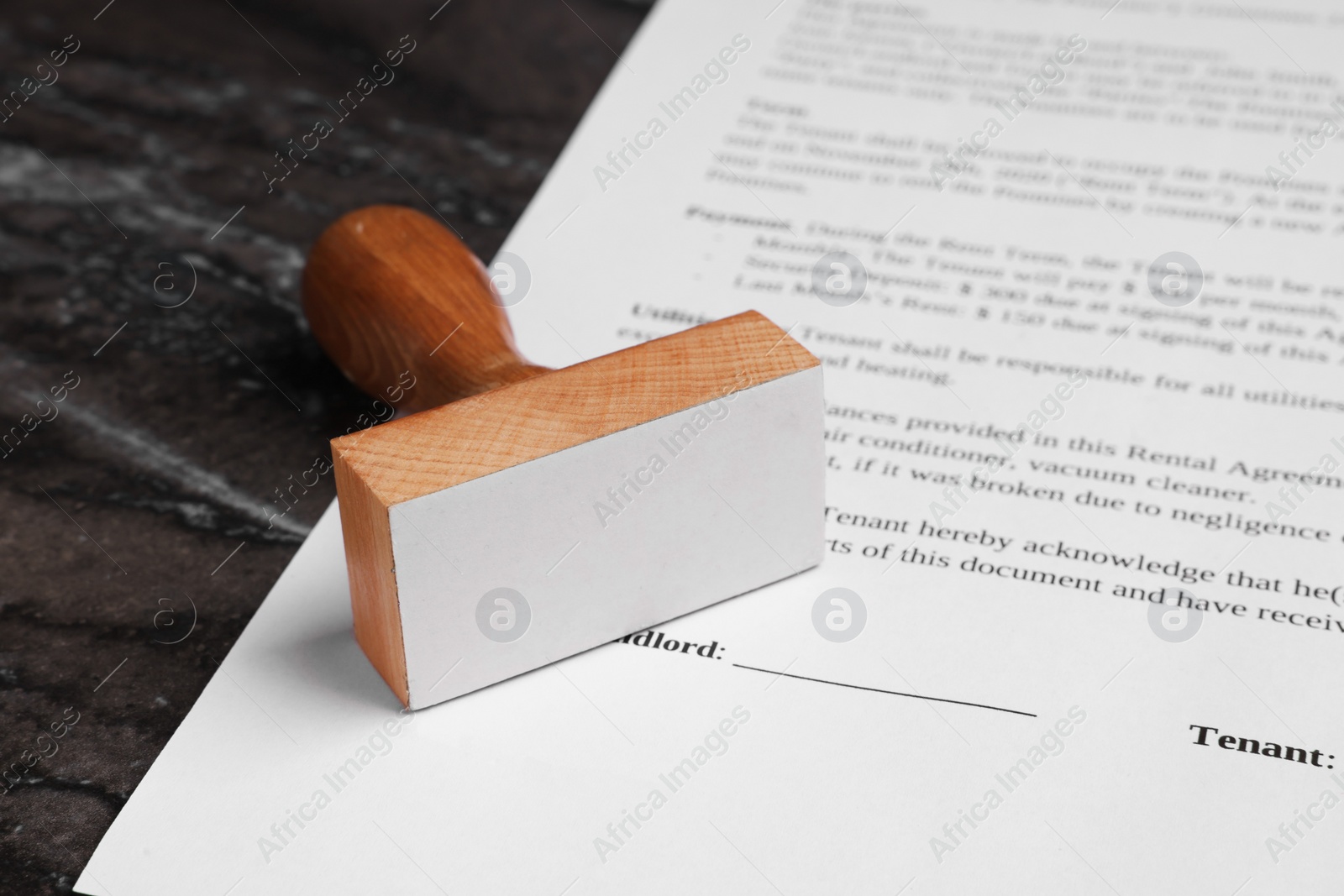 Photo of One stamp tool and document on dark marble table, closeup