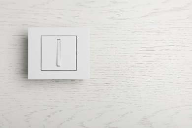 Photo of Light switch on white wooden background, top view. Space for text