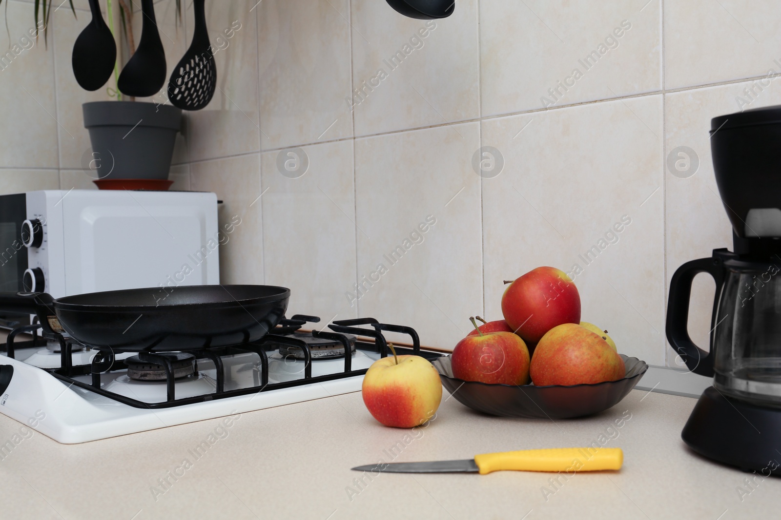 Photo of Fresh apples and coffeemaker near gas cooktop in kitchen