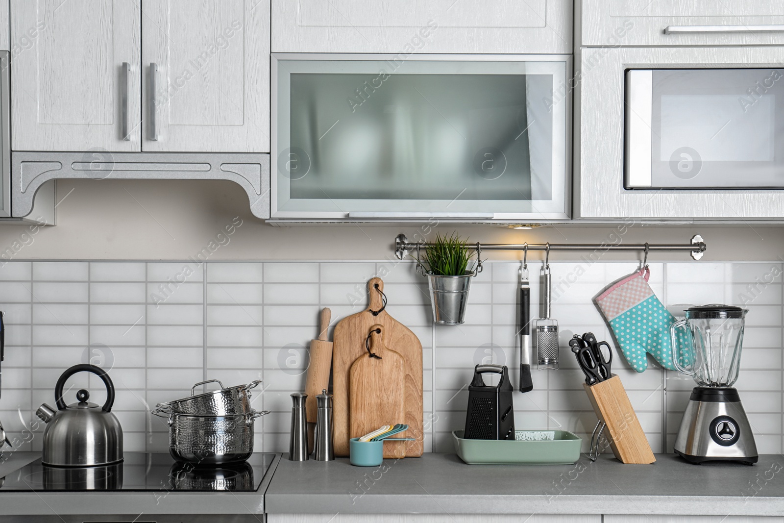 Photo of Kitchen interior with clean cookware, appliances and dish cabinet