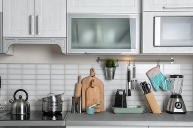 Photo of Kitchen interior with clean cookware, appliances and dish cabinet