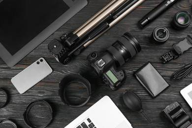 Flat lay composition with camera and video production equipment on black wooden table