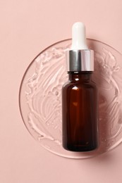 Bottle of cosmetic serum on pink background, top view