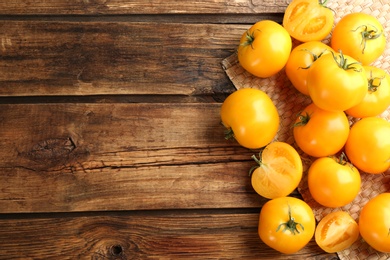 Photo of Ripe yellow tomatoes on wooden table, flat lay. Space for text