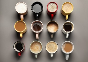 Photo of Many different cups with aromatic coffee on grey table, flat lay