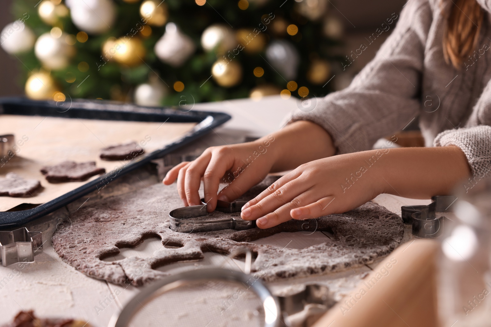 Photo of Little child making Christmas cookies at white wooden table, closeup