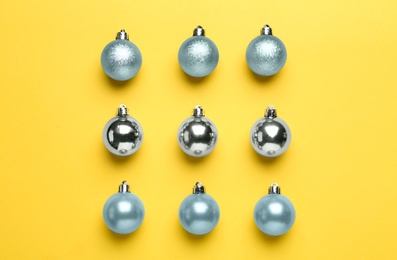 Photo of Shiny Christmas balls on yellow background, flat lay