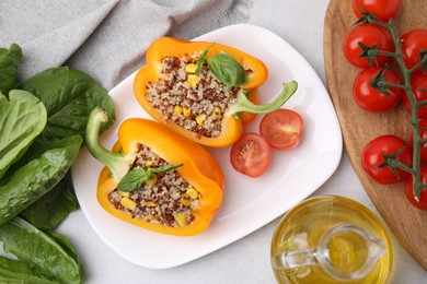 Photo of Quinoa stuffed bell pepper with basil, oil and tomato on light table, flat lay