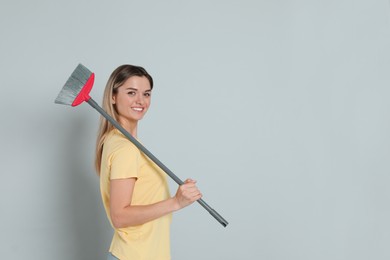 Photo of Young woman with broom on grey background, space for text